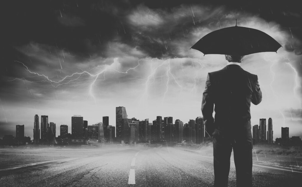 Un hombre con un paraguas mira una ciudad sobre la que hay una tormenta, representando la idea de las distopías críticas. Imagen de RomoloTavanni en Getty Images Pro (licencia Canva Pro).