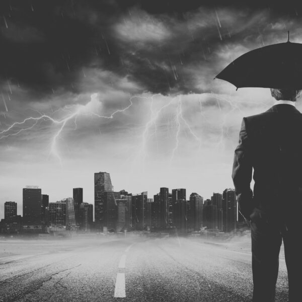 Un hombre con un paraguas mira una ciudad sobre la que hay una tormenta, representando la idea de las distopías críticas. Imagen de RomoloTavanni en Getty Images Pro (licencia Canva Pro).