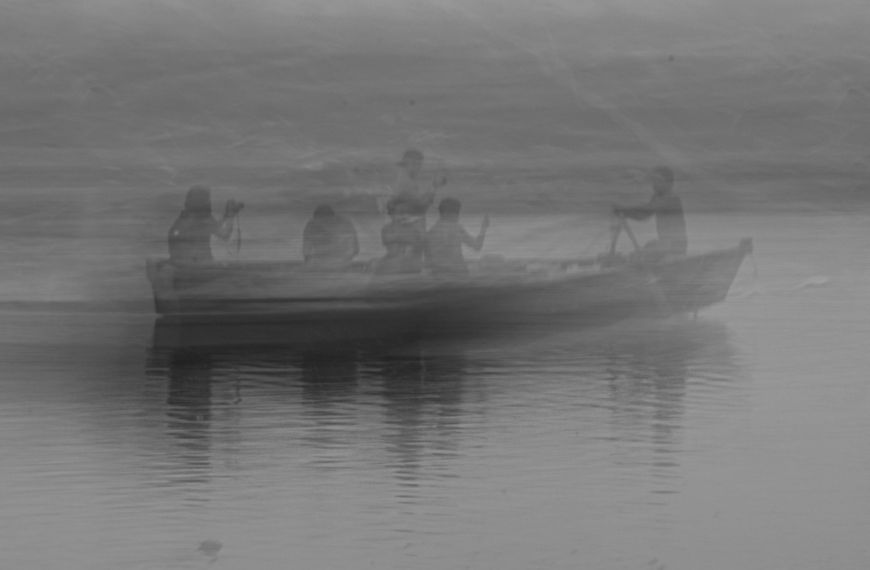 Existimos pero, ¿quienes somos? En la imagen se ve una barcaza con gente remando, difuminada entre la niebla.